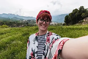 People In Nature Prints: Woman doing a selfie in a meadow looking happy wearing a flowers shirt