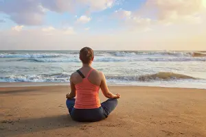 Flexible Prints: Woman doing yoga - meditating and relaxing in Padmasana Lotus Pose outdoors at tropical beach on sunset