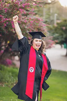 Student Prints: Woman excited to be graduating college, wearing a graduation gown/cap