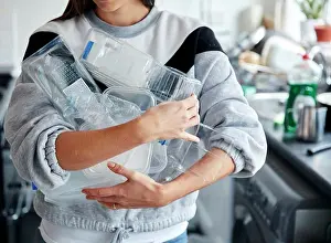Conservation Prints: Woman holding armful of used plastic containers in kitchen