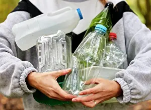 Cleaning Prints: Woman holding armful of used plastic packaging and bottles