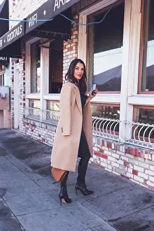 Mixed Prints: Woman holding her phone on the sidewalk in front of restaurant
