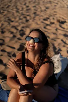 20 To 25 Years Prints: Woman holds a seashell on her nose on the beach