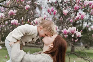 Spring Time Prints: A woman kiss her little daughter near a blooming magnolia tree