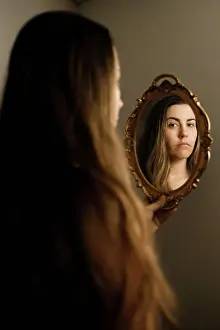 Sorrow Prints: A woman looking at herself in a vintage mirror