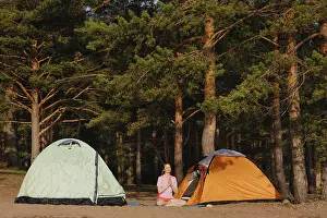 Hike Prints: Woman in lotus position and namaste among tents in the forest