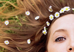 Make Up Prints: Woman lying on a meadow wearing daisies in her hair, close-up