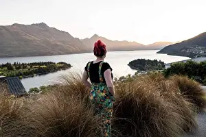 Woman overlooking Queenstown and lake, at sunset in New Zealand