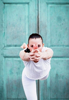 Agility Prints: Woman practicing yoga, on one leg in front of door, portrait