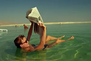 Newspaper Prints: Woman reading a newspaper whilst floating in the Dead Sea, Israel, Middle East