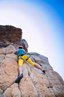 Adventure Prints: Woman rock climbing on cliffs, low angle view