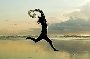 Newport Prints: A woman with a scarf leaps on the beach in Newport, Oregon