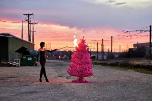 Ritual Prints: Woman sets fire to pink Christmas tree in industrial area at sunset