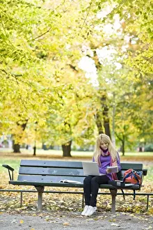 Communications Prints: A woman sitting on bench in a park using a laptop, Stockholm, Sweden