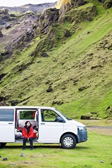 Contemplating Prints: woman sitting in the door of her camper van on rural campsite