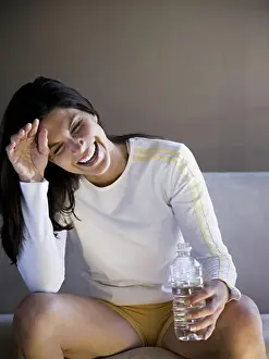 Refreshment Prints: Woman sitting on sofa with bottled water smiling