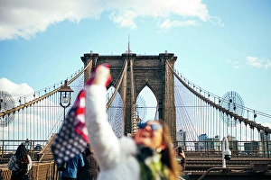 Quality Time Prints: Woman standing on Brooklyn Bridge holding the American flag, New York, United States