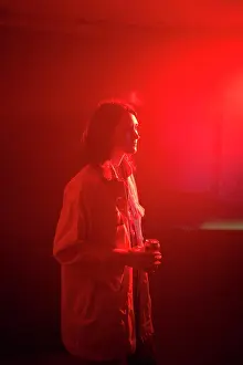 Thoughtful Prints: A woman stands in a red-lit room holding a drink