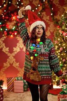 Sweater Prints: Woman wearing festive ugly Christmas sweater with reindeer and lights holding Santa hat