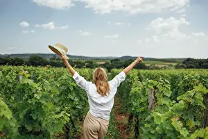 Schoen Prints: Woman, wearing a hat, in a vineyard in the sun Joyful woman