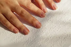 Disability Prints: Woman's fingers on a book page with braille