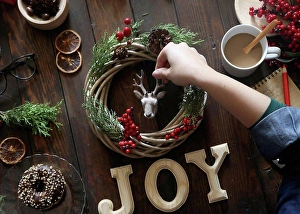 Skilled Prints: Woman's hand decorating Christmas wreath on wooden table