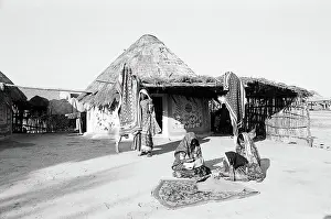 Women in front of round shaped homes bhungas embroidering fabrics