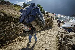 Hike Prints: A worker carries a water tank on his bank in Namche Bazaar, Nepal