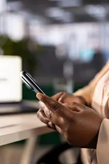 Electronic Prints: Worker in startup office compiling financial reports using phone