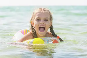 Swims Prints: Six year old girl bathing in the sea with his mouth open in pleasure Six-year girl bathes with a swimming circle