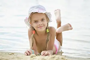 Nahaufnahme Prints: Six year old girl lying on the sand on the beach Six year old girl Europeans in panama lying on his stomach on the sand
