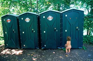 Toilet Prints: Yound child waiting naked outside line of outhouses or portable toilets at Stockholm city beach park in summer