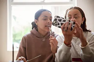 Texting Prints: Young adult sisters eating and using smart phone