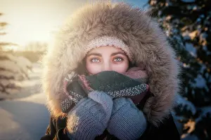 Frosty Prints: Young attractive female in warm clothing with fur joyful laughing beside covered snow conifer tree