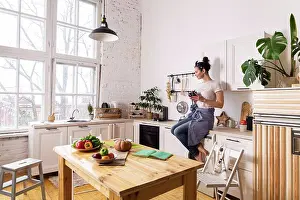 Knife Prints: Young and beautiful housewife woman cooking in a white kitchen