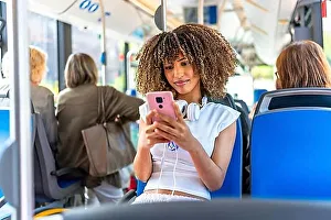 Local Transport Prints: Young beauty latin woman with curly hair and casual clothes using phone distracted sitting on public bus