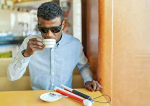 Disability Prints: young blind african man having a coffee