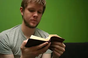 Married Prints: Young blond man reading the Bible with bright green background
