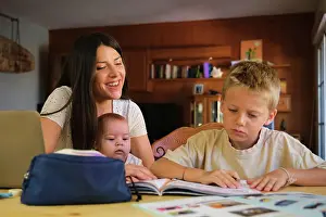 Small Group Prints: Young boy doing homework with mother and baby boy at home