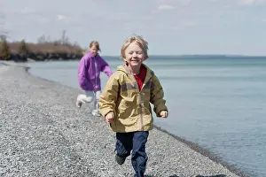 8 To 9 Years Prints: Young Boy Running Ahead Of Young Girl On Pebble Beach Of Lake Ontario, Ontario