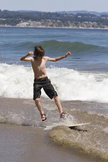 Surfing Prints: A young boy skim boarding on the beach on the Pacific Ocean in Santa Cruz, California