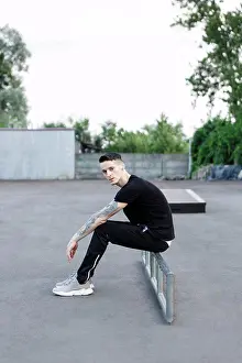 Lockdown Prints: young brunette man sitting alone on an asphalt skate playground