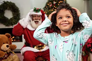 Grandfather Prints: Young child in living room with a Christmas background and Santa mimicking her moves behind her