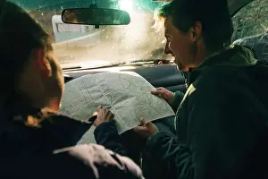 Hood Prints: A young couple looks at the map on a road trip