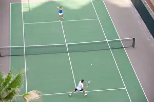 Young couple playing tennis in the court of a tourist resort