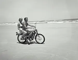Full Length Prints: Young couple riding motorcycle on beach