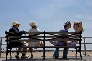 Senior Women Prints: Young couple and a senior couple sitting on a bench