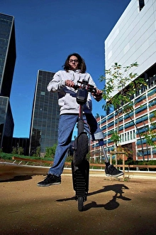 Handicapped Prints: Young disabled man practicing stunt on electric push scooter in playground against buildings in city