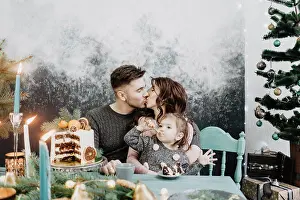 Garland Prints: Young family with a daughter in festive outfits at a served table with candles