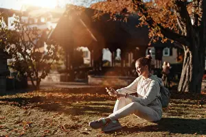 Attractive Prints: Young Fashionable Teenage Girl With Smartphone In Europian Park In Autumn Sitting At Smiling